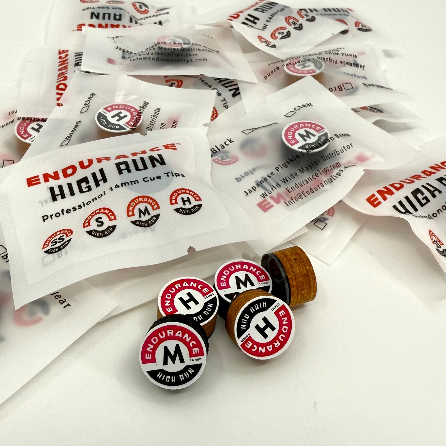 image of a mixed assortment of pool cue tips Endurance brand, 14mm 8 layer Japanese pig skin. Brown and Black in white packaging.